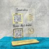 Black acrylic qr code stand on a wooden counter displaying a golden Paytm scanner and Instagram code.