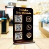 Black acrylic social media stand on a wooden counter displaying Instagram and GPay codes.